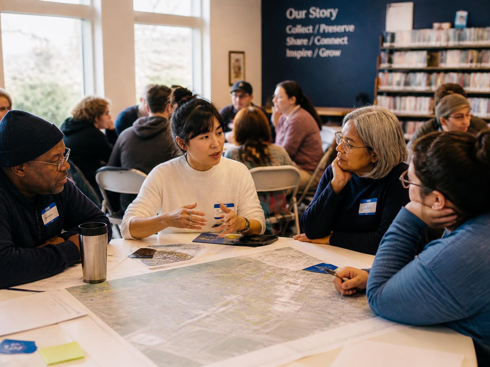 Residents reviewing neighborhood maps together at a community meeting in a public library